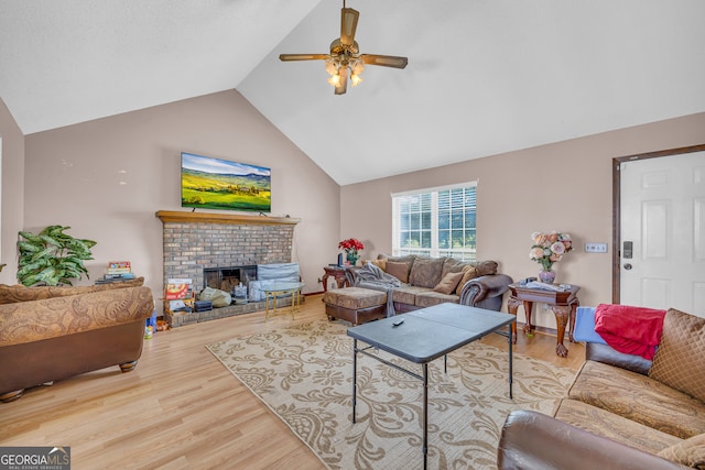 living room featuring ceiling fan, lofted ceiling, a fireplace, and light hardwood / wood-style flooring