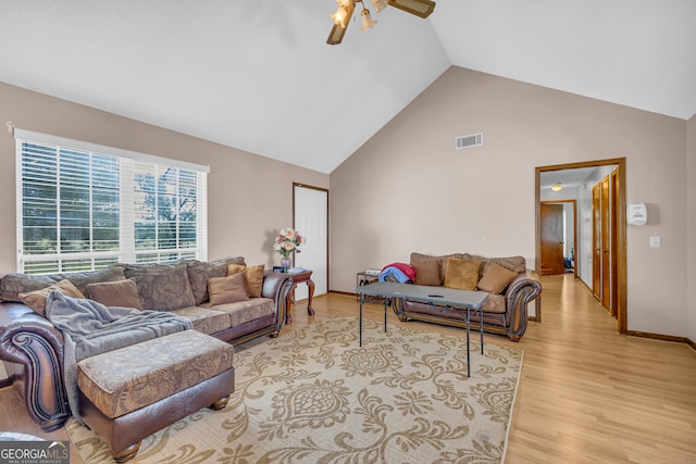 living room with ceiling fan, light hardwood / wood-style floors, and vaulted ceiling