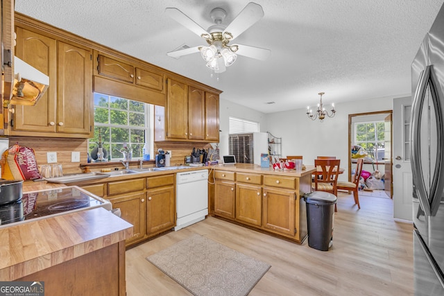 kitchen featuring sink, hanging light fixtures, light hardwood / wood-style flooring, kitchen peninsula, and white dishwasher