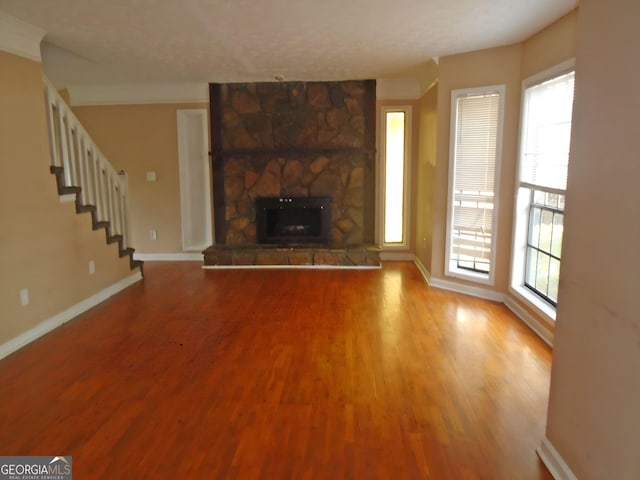 1038 Ascot Ct, Riverdale, GA 30296 - unfurnished living room with hardwood / wood-style flooring, plenty of natural light, a stone fireplace, and a textured ceiling