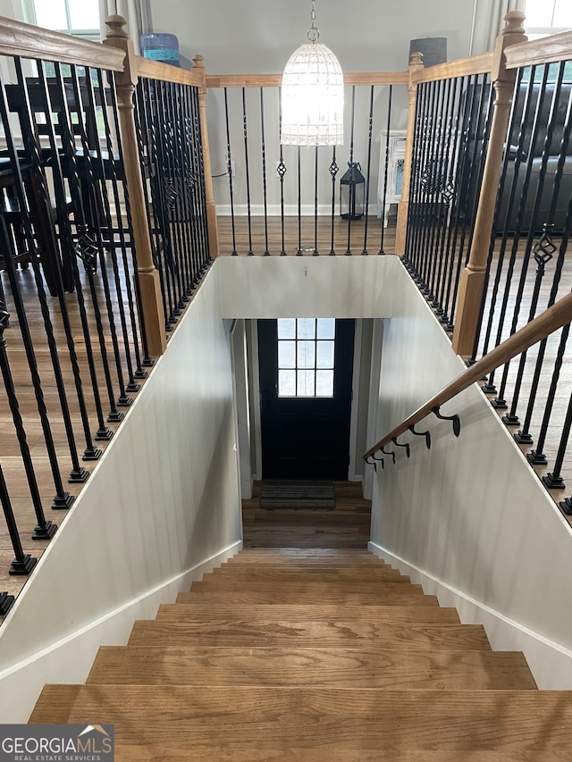 staircase featuring wood-type flooring and a chandelier