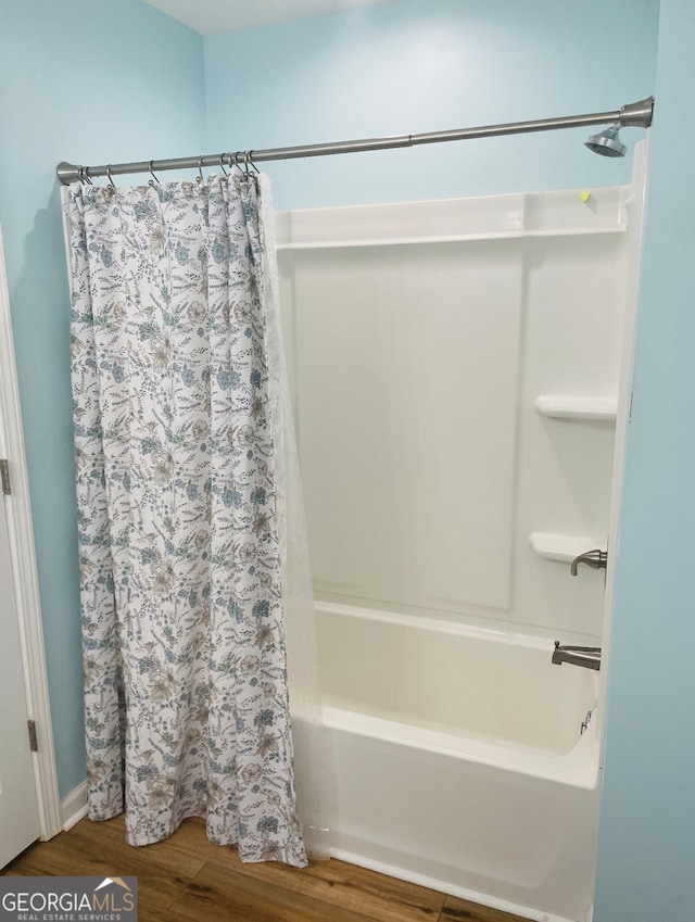 bathroom with hardwood / wood-style floors and shower / bathtub combination with curtain