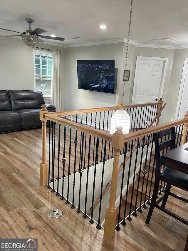 stairway with ornamental molding, hardwood / wood-style flooring, and ceiling fan