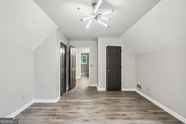 additional living space with a notable chandelier, lofted ceiling, and hardwood / wood-style flooring