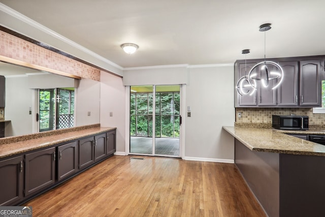 kitchen featuring backsplash, dark stone counters, crown molding, decorative light fixtures, and kitchen peninsula