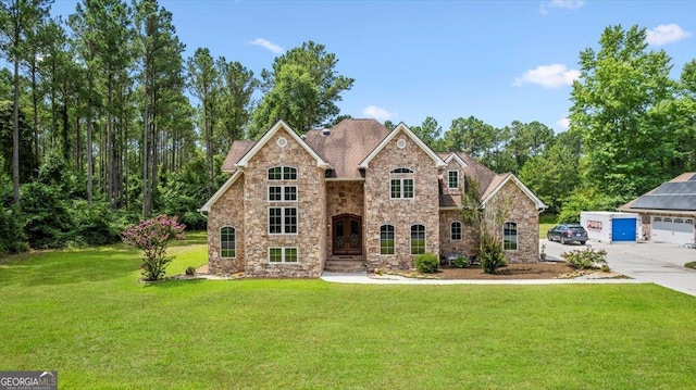 view of front of home with a garage, a front yard, and an outbuilding