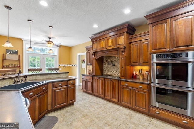 kitchen featuring a textured ceiling, sink, pendant lighting, and stainless steel double oven