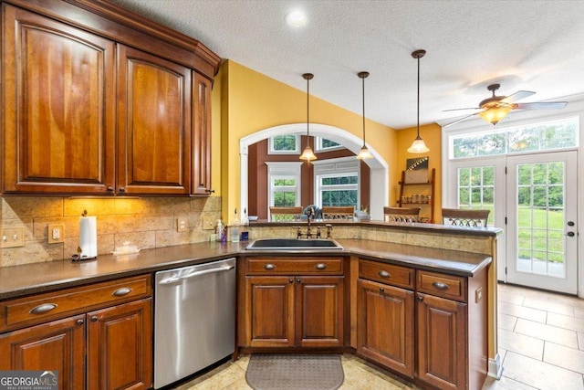 kitchen with a textured ceiling, decorative light fixtures, stainless steel dishwasher, and sink