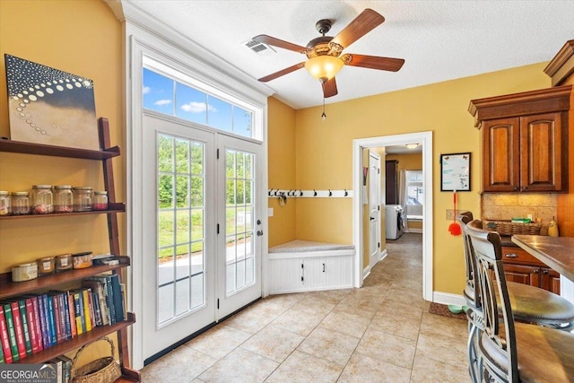 doorway with ceiling fan, a textured ceiling, light tile patterned floors, and washer / clothes dryer