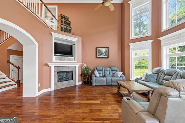 living room with a towering ceiling, wood-type flooring, and a tile fireplace