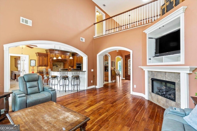 living room featuring dark wood-type flooring, a fireplace, and a high ceiling