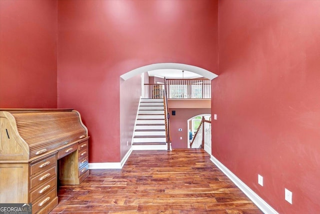 stairs featuring a towering ceiling and hardwood / wood-style floors