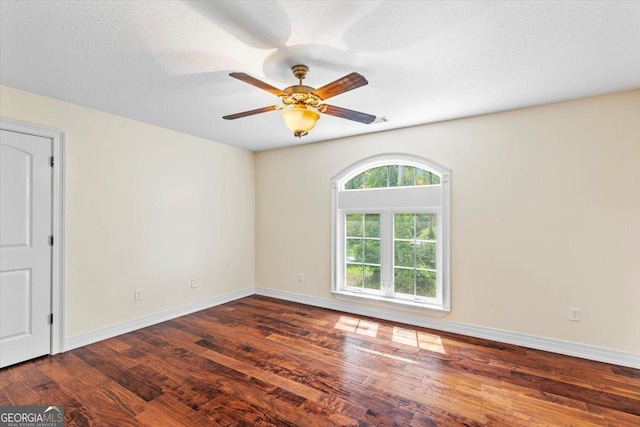 unfurnished room with a textured ceiling, dark wood-type flooring, and ceiling fan