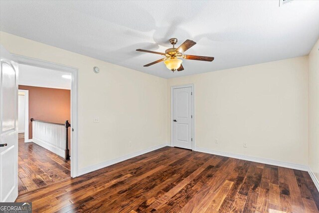 empty room with ceiling fan and dark hardwood / wood-style flooring