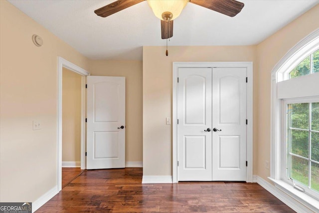 unfurnished bedroom featuring ceiling fan, a closet, dark hardwood / wood-style floors, and multiple windows