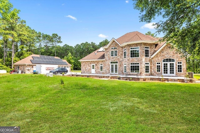 rear view of house with solar panels and a yard