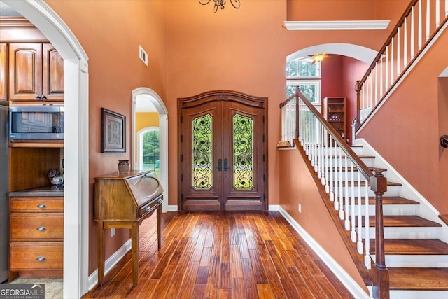 foyer entrance featuring hardwood / wood-style flooring, a high ceiling, and french doors