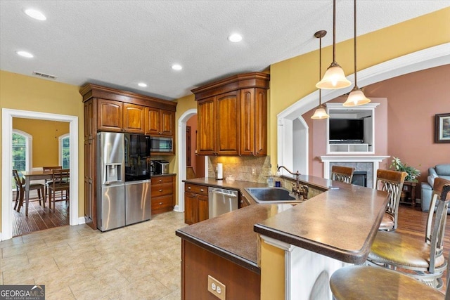 kitchen with pendant lighting, appliances with stainless steel finishes, a kitchen bar, tasteful backsplash, and sink