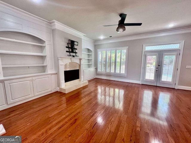 unfurnished living room featuring french doors, ornamental molding, hardwood / wood-style flooring, built in features, and ceiling fan