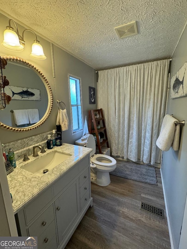 bathroom featuring a textured ceiling, vanity, wood-type flooring, and toilet