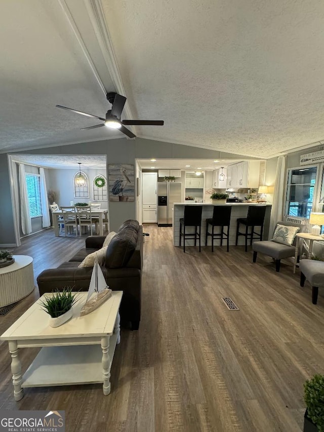 living room with hardwood / wood-style flooring, a textured ceiling, vaulted ceiling, and ceiling fan