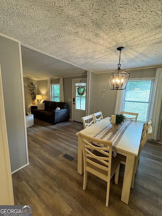 dining area featuring an inviting chandelier, dark hardwood / wood-style flooring, and a textured ceiling