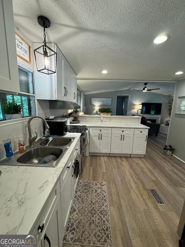 kitchen featuring white cabinets, sink, light hardwood / wood-style floors, decorative light fixtures, and ceiling fan with notable chandelier