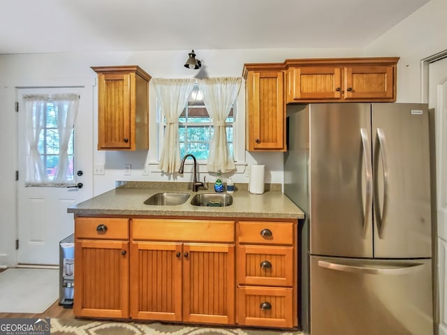 kitchen featuring sink, light wood-type flooring, and stainless steel refrigerator