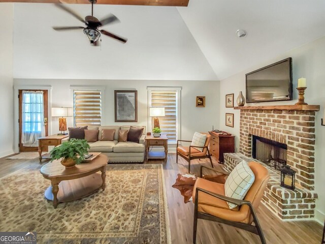 living room featuring high vaulted ceiling, wood-type flooring, ceiling fan, and a fireplace