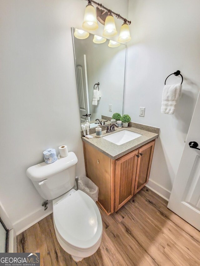 bathroom featuring wood-type flooring, vanity, and toilet