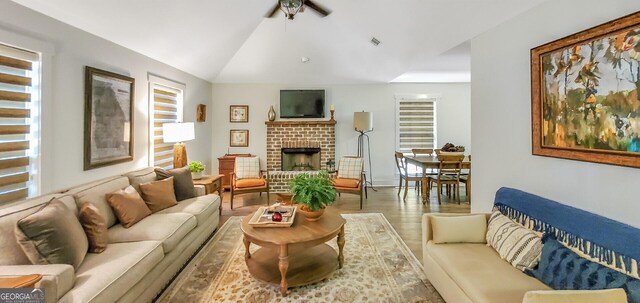 living room featuring a healthy amount of sunlight, a fireplace, vaulted ceiling, and hardwood / wood-style floors