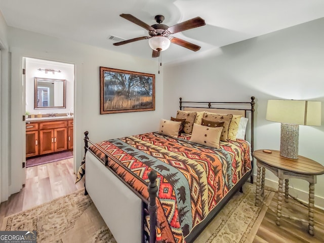 bedroom featuring ceiling fan, light hardwood / wood-style flooring, and ensuite bath