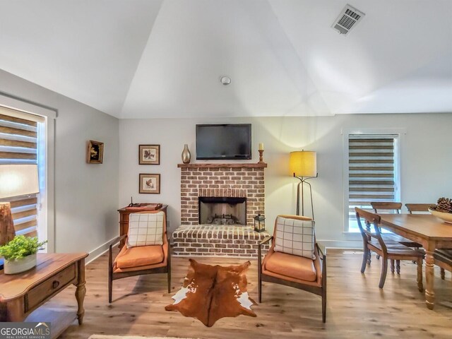 interior space featuring wood-type flooring, a fireplace, and vaulted ceiling