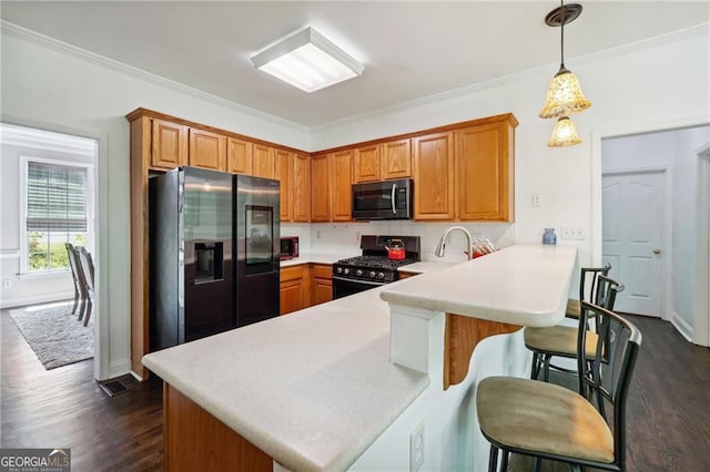 kitchen with dark wood-type flooring, hanging light fixtures, appliances with stainless steel finishes, tasteful backsplash, and kitchen peninsula