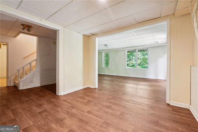 unfurnished living room with wood-type flooring and a drop ceiling