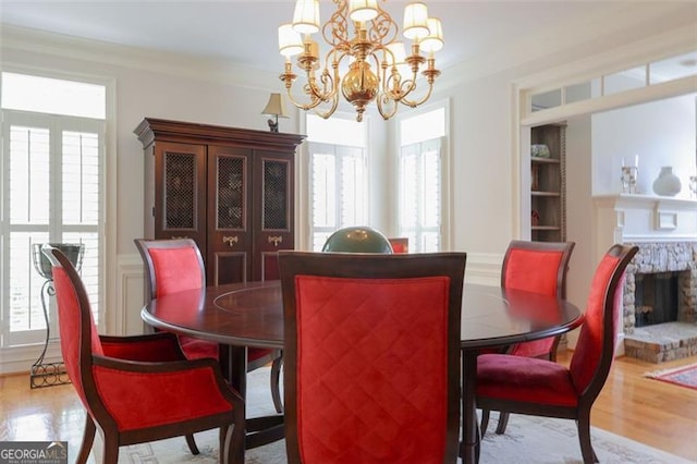 dining space with a healthy amount of sunlight, ornamental molding, light hardwood / wood-style flooring, and a chandelier