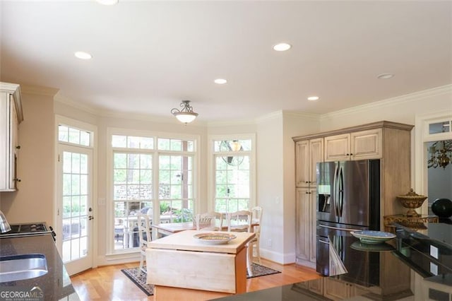 kitchen with a wealth of natural light, ornamental molding, light hardwood / wood-style floors, and stainless steel refrigerator with ice dispenser