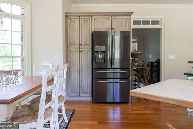 kitchen featuring crown molding, stainless steel fridge, cream cabinets, and wood-type flooring