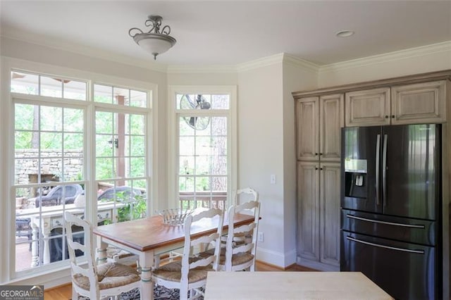 dining space with ornamental molding and light hardwood / wood-style flooring