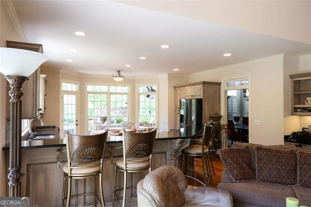 kitchen with ornamental molding, kitchen peninsula, hardwood / wood-style floors, stainless steel refrigerator with ice dispenser, and sink