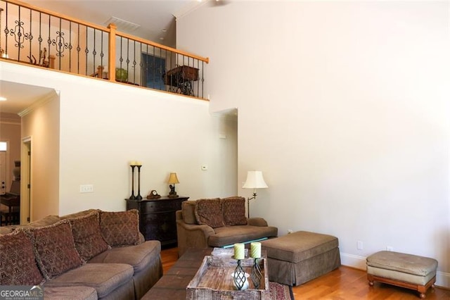 living room with a towering ceiling, ornamental molding, and hardwood / wood-style flooring