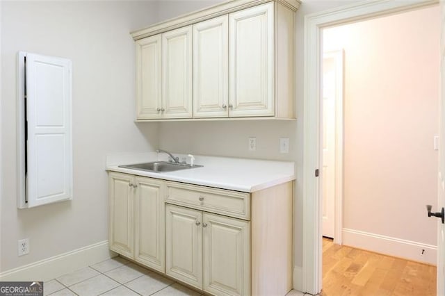 kitchen with light hardwood / wood-style floors, sink, and cream cabinetry