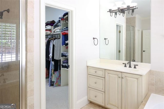 bathroom featuring a shower with shower door, vanity, and ornamental molding