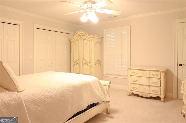 carpeted bedroom featuring multiple closets, ceiling fan, and crown molding