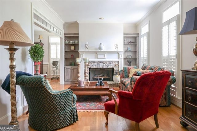 living room with crown molding, a fireplace, built in shelves, and hardwood / wood-style floors