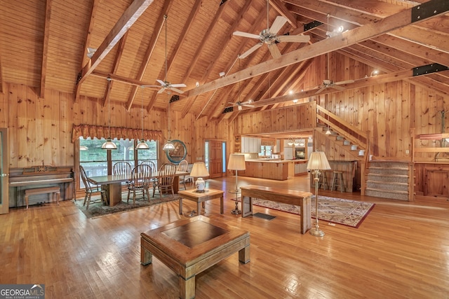 living room with beamed ceiling, light wood-type flooring, high vaulted ceiling, and wood ceiling