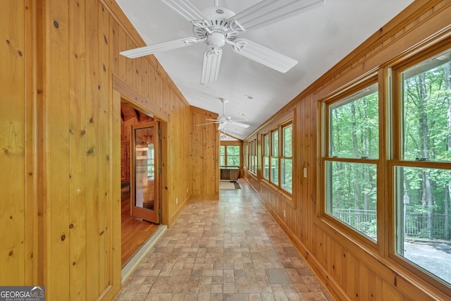 corridor featuring wooden walls, crown molding, and lofted ceiling