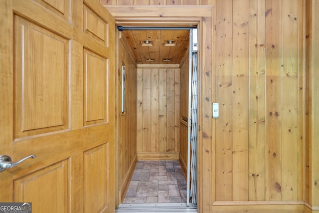 hallway featuring wooden walls