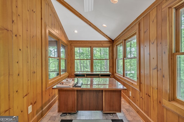 unfurnished office featuring wooden walls, plenty of natural light, and vaulted ceiling