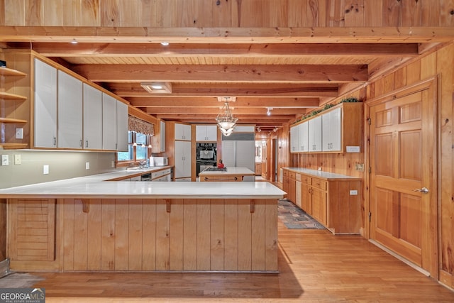 kitchen with kitchen peninsula, decorative light fixtures, beamed ceiling, and wood walls